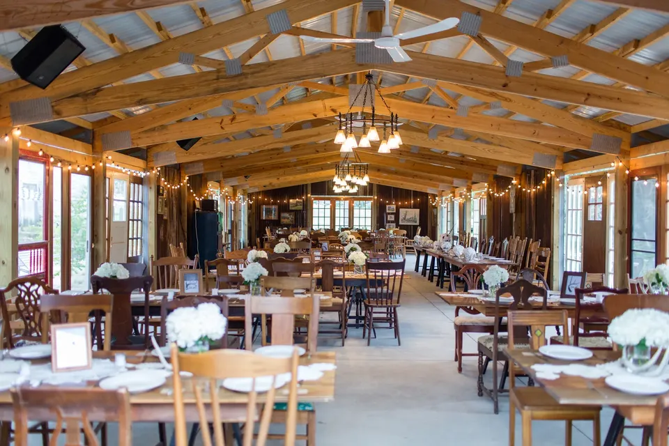 The reception hall set with long wooden tables beneath a wood beamed ceiling