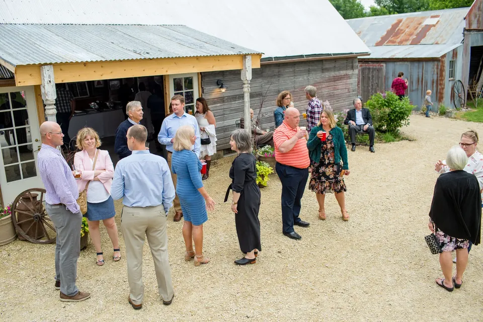 Guests gathered outdoors between the farm buildings