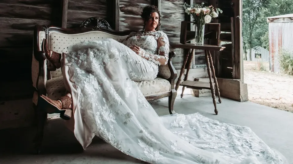 A bride with a long lace train arranged across a vintage settee