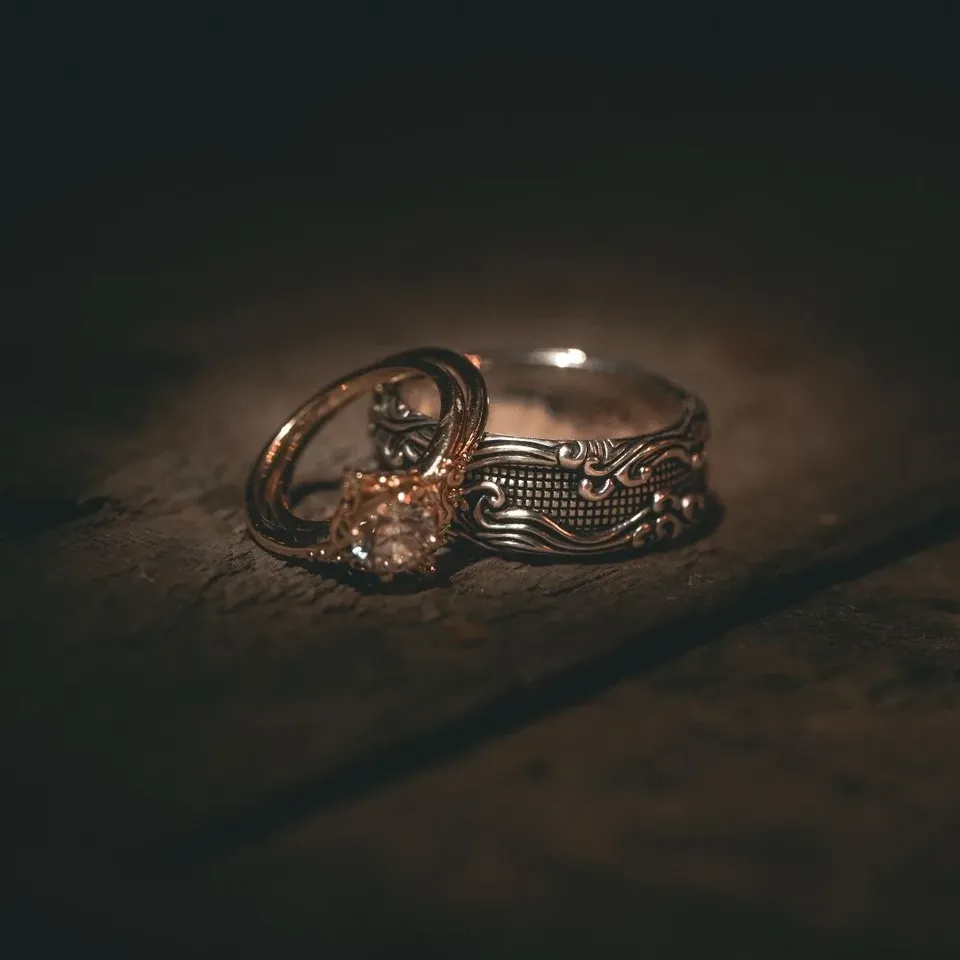 Two wedding rings resting on a dark reflective surface