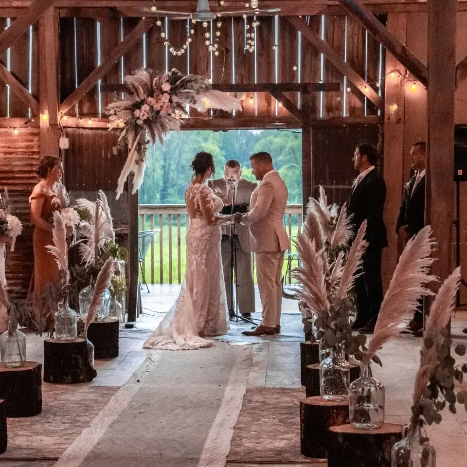 A ceremony in the open barn doorway framed by dried florals